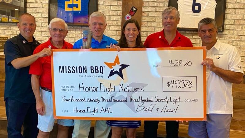 Six people standing holding large check with Mission BBQ logo on it