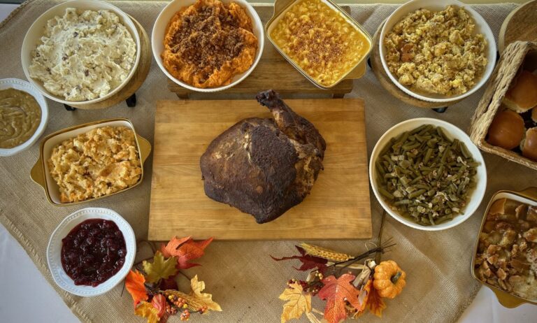 XL Holiday Turkey Meal shown from above with 6 side options, gravy, cranberry sauce and dessert. The table is decorated with fall decor.